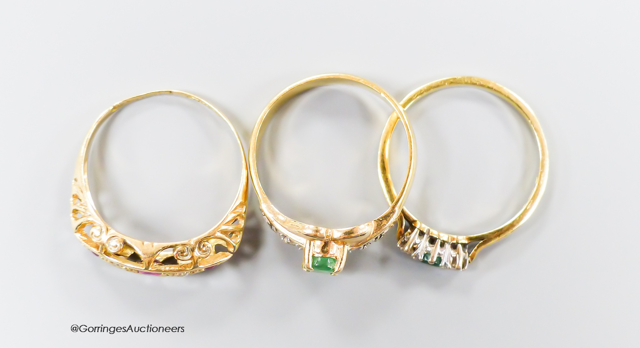 Three assorted modern 18ct gold and gem set rings, including emerald and diamond, ruby and diamond, gross 6.9 grams.